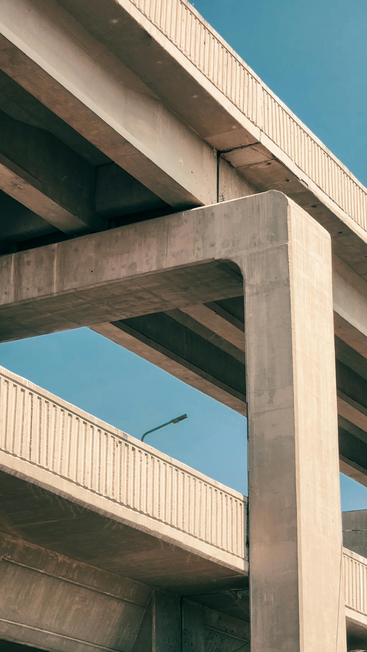 A towering concrete overpass structure with a clear blue sky background, showcasing modern architecture.