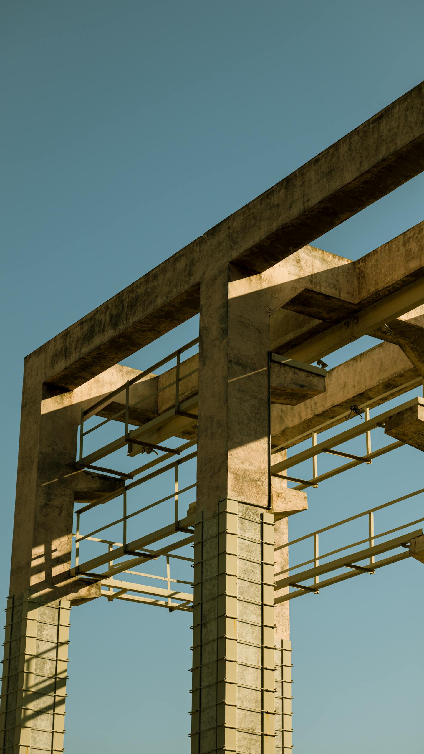Vertical view of a concrete construction frame against a clear blue sky, showcasing urban architecture.